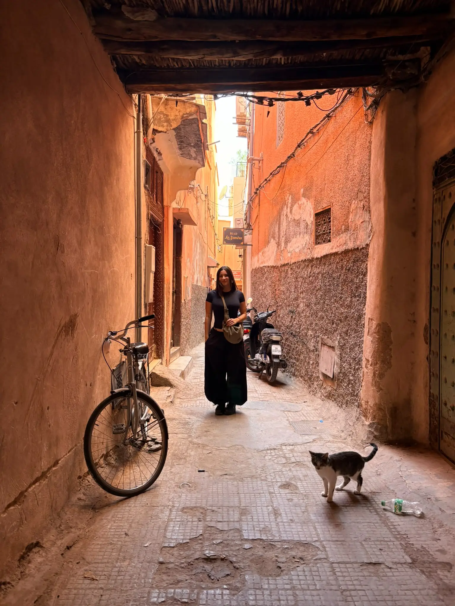 Amalia en un callejón de la medina de Marrakech, con una bici y un gato