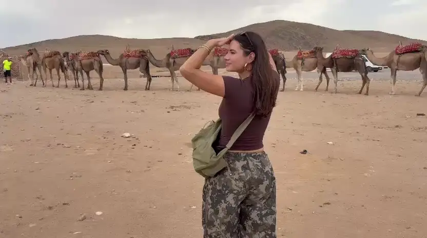 Amalia frente a una fila de camellos en el desierto